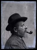 Ritratto di Olindo Guerrini di profilo con il cappello e la pipa in bocca: set fotografico allestito nel cortile interno della Biblioteca Universitaria di Bologna