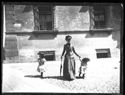 Una donna con due bambine attraversa la via Mazzini, già Strada Maggiore, verso il quadriportico della chiesa di Santa Maria dei Servi: Bologna