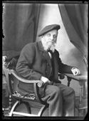 Ritratto di Olindo Guerrini con un berretto a basco francese seduto su una sedia di tipo savonarola