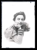 Ritratto di Lina Guerrini sorridente con un abito con la manica gigot, appoggiata con un gomito sul tavolino
