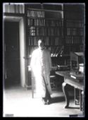 Ritratto di Guido Guerrini con il camice bianco davanti ad uno scaffale della Biblioteca Universitaria di Bologna