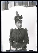 Ritratto di una giovane donna con un cappellino e la lorgnette tra le mani: set fotografico allestito nel cortile interno della Biblioteca Universitaria di Bologna