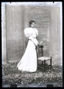 Caterina Frontali con un abito con la manica gigot, in piedi accanto ad una sedia nel cortile interno della Biblioteca Universitaria di Bologna