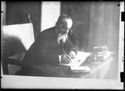 Ritratto di Olindo Guerrini, da una fotografia di Mario Pozzi, seduto allo scrittoio con un pennino e un taccuino
