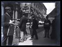 Un uomo con dei giornali e altre persone nella via Carlo Alberto davanti al palazzo Giureconsulti: prospetto della via Carlo Alberto: Milano