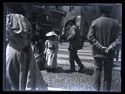 Una donna e una bambina attraversano la via Carlo Alberto: prospetto della via Mercanti con il palazzo della Ragione: Milano