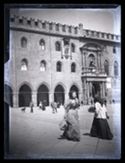 Due donne a passeggio, in direzione opposta, in piazza Vittorio Emanuele II: prospetto del Palazzo Comunale: Bologna