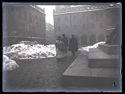 Una donna e due uomini a passeggio, tra i cumuli di neve, davanti alla statua equestre di Vittorio Emanuele II:  prospetto della piazza Vittorio Emanuele II con il palazzo dei Notai e il Palazzo Comunale: Bologna