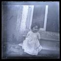 Una bambina seduta su uno scalino dell’ingresso di una casa