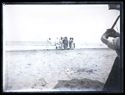 Un gruppo di bagnanti con l’accappatoio e un pescatore con alcune donne intorno alla cesta del pescato sulla spiaggia davanti al mare: Bellaria