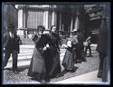 Due donne e altre persone attraversano la via Carlo Alberto davanti al palazzo Giureconsulti: Milano