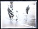 Una donna con un bambino tenuto per mano sulla battigia e un uomo che li raggiunge dalla riva: Bellaria