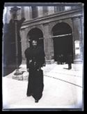 Una donna che guarda l’obiettivo fotografico a passeggio in piazza del Nettuno: prospetto del portico della Gabella nella via Ugo Bassi: Bologna