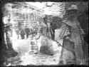 Una donna che guarda l’obiettivo fotografico e una donna con una bambina tenuta per mano, a passeggio in piazza Vittorio Emanuele II: prospetto del Palazzo Comunale in piazza del Nettuno: Bologna