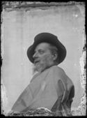 Ritratto di Olindo Guerrini di profilo con un cappello a tesa larga e un mantello: set fotografico allestito nel cortile interno della Biblioteca Universitaria di Bologna