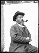 Ritratto di Olindo Guerrini di profilo con il cappello e la pipa in bocca: set fotografico allestito nel cortile interno della Biblioteca Universitaria di Bologna