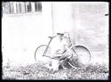Olindo Guerrini inginocchiato si appresta a gonfiare la ruota anteriore della bicicletta nel cortile interno della Biblioteca Universitaria di Bologna