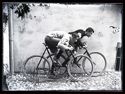 Guido Guerrini e un giovane uomo con la fascetta al braccio, simulano una gara sulle biciclette da corsa