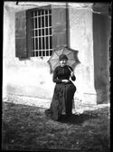 Ritratto di una donna sorridente con il parasole seduta su uno sgabello nel giardino sul lato est della villa di Gaibola: Bologna