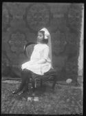 Ritratto di una bambina con l’abito della prima comunione: set fotografico allestito con un telo damascato