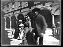 Un uomo e tre donne attraversano la via dell’Indipendenza: prospetto del portico della casa Coccapani: Bologna
