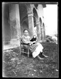 Lina Guerrini seduta su una seggiolina con una bambola nel giardino davanti al loggiato della villa di Gaibola, detta la Vigna: Bologna