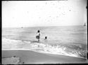 Una giovane donna con la gonna sollevata che guarda l’abiettivo fotografico e una anziana seduta nella riva: Bellaria