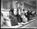 Tre donne che fanno conversazione e alcuni uomini, seduti sullo zoccolo della basilica di San Petronio oltre il portale destro: piazza Vittorio Emanuele II: Bologna