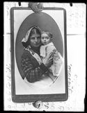 Ritratto di una donna con una bambina in braccio da una fotografia di Andrea Vidau e figlio puntata ad una pagina manoscritta con istruzioni tecniche per lo sviluppo delle lastre negative