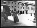 Una bambina con un cesto e una donna a passeggio in piazza Vittorio Emanuele II all’imbocco della via de’ Pignattari: prospetto del Palazzo Comunale: Bologna