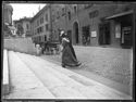 Due donne davanti alla scalinata della basilica di San Petronio, tre uomini seduti sullo zoccolo e una carrozza ferma davanti allo spaccio di liquori nella via de’ Pignattari: Bologna