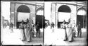 Una donna divertita, che guarda l’obiettivo fotografico, attraversa con una donna e altri la via dell’Indipendenza:  prospetto della via Ugo Bassi e del portico della Gabella: Bologna