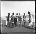 Un uomo con l’accappatoio, due donne con l’abito lungo, due giovani uomini in costume da bagno e Guido Guerrini sulla spiaggia davanti al mare: Bellaria