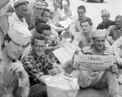 Un gruppo di lavoratori edili durante la pausa del pranzo leggono il quotidiano con l’annuncio di uno sciopero per il giorno successivo. Roma, 9.5.1963