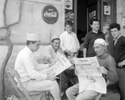 Un gruppo di lavoratori edili durante la pausa del pranzo leggono il quotidiano con l’annuncio di uno sciopero per il giorno successivo. Roma, 9.5.1963