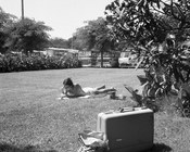 Turista americana che legge mentre prende il sole nei giardini di fronte alla stazione Termini. Roma, 13.8.1970 
