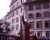 Adolfo Consolini, bandiera dell’atletica italiana specialista nel lancio del disco, sulla Cordonata capitolina di fronte e fotografi, giornalisti e pubblico, sorregge la torcia olimpica delle Olimpiadi invernali. Roma, 22 gennaio 1956